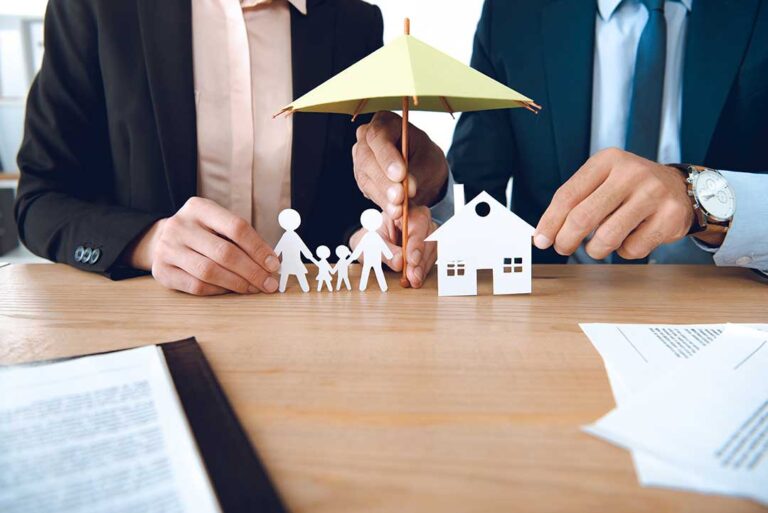 Person sitting at a wooden table carefully reading through an insurance policy document with a pen in hand.