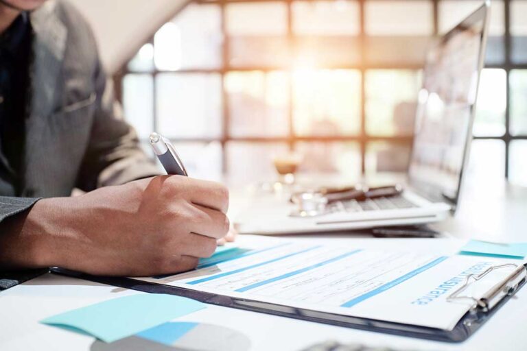 Person holding an insurance ID card and checking details with a pen at a kitchen table.