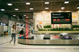 Traveler reports a missing suitcase at an airport baggage counter while holding a claim tag and boarding pass.